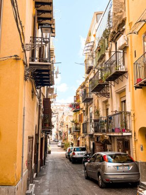 Narrow streets on the old town of Palermo in Sicily, Italy. Gorgeous architecture in the sunshine. Scooters are parked near the walls, and greenery is in the pots.