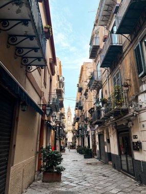 Narrow streets on the old town of Palermo in Sicily, Italy. Gorgeous architecture in the sunshine. Scooters are parked near the walls, and greenery is in the pots.