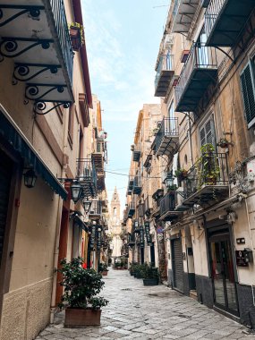 Narrow streets on the old town of Palermo in Sicily, Italy. Gorgeous architecture in the sunshine. Scooters are parked near the walls, and greenery is in the pots.