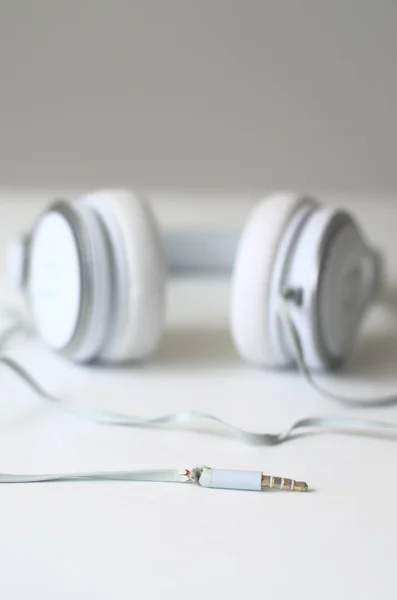 White leather headphones on the side. White headphones on the white table and on the white background.