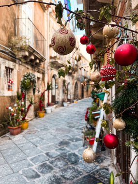 Narrow streets on the old town of Syracuse in Sicily, Italy. Gorgeous architecture in the sunshine. Scooters are parked near the walls, and greenery is in the pots.