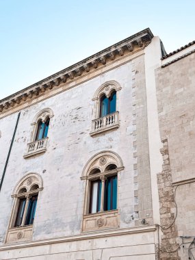 Narrow streets on the old town of Syracuse in Sicily, Italy. Gorgeous architecture in the sunshine. Scooters are parked near the walls, and greenery is in the pots.
