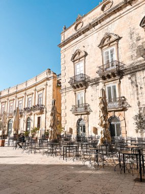 Narrow streets on the old town of Syracuse in Sicily, Italy. Gorgeous architecture in the sunshine. Scooters are parked near the walls, and greenery is in the pots.