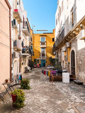 Narrow streets on the old town of Syracuse in Sicily, Italy. Gorgeous architecture in the sunshine. Scooters are parked near the walls, and greenery is in the pots.