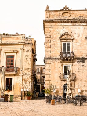 Narrow streets on the old town of Syracuse in Sicily, Italy. Gorgeous architecture in the sunshine. Scooters are parked near the walls, and greenery is in the pots.