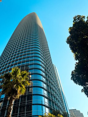 San Francisco 'nun cam ve beton gökdelenleri tepeden tırnağa görünüyor. Güneşli bir günde dev bina ışıldıyor, yollar az trafikle kesişiyor..