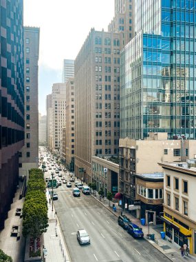 San Francisco 'nun cam ve beton gökdelenleri tepeden tırnağa görünüyor. Güneşli bir günde dev bina ışıldıyor, yollar az trafikle kesişiyor..