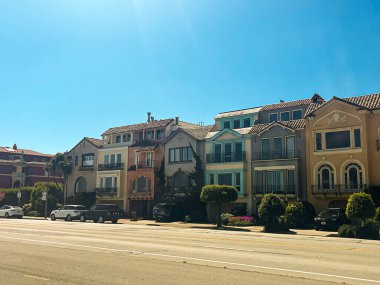 San Fransisco 'daki evler geniş yolun yakınında yer alıyor. Aydınlık yaz havasında, açık gökyüzü olan şirin aile evleri. Yolda trafik yok..