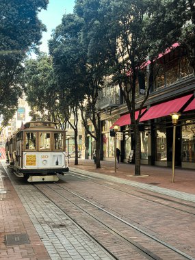 San Francisco caddesindeki tramvay. Şehrin dik tepelerini aşmak için güzel bir ulaşım fırsatı. Tramvay rayları güneşte parlıyor. Ağaçlı sokaklar.