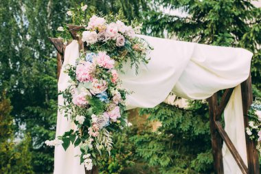 Açık hava düğün töreni için çiçeklerle süslenmiş güzel bir düğün kemeri.                  