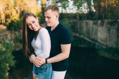 Mutlu genç çift yazın nehir kıyısında sarılıyor..       