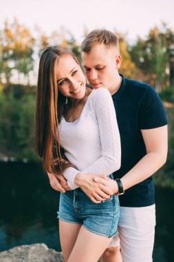 Nehir ve ormanın arka planında birbirini seven güzel genç bir çift. 