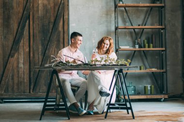 Birbirine aşık genç bir çift tahta masada oturuyor ve ellerinde bardaklarla.          
