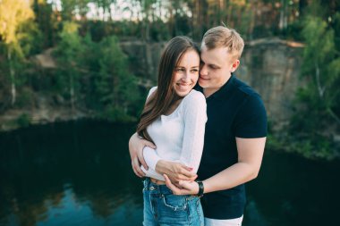 Mutlu genç çift yazın nehir kıyısında sarılıyor..       