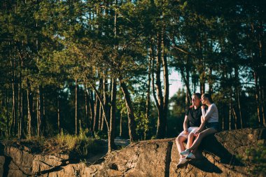 Ormanda kayaların üzerinde oturan genç ve güzel bir çift.     