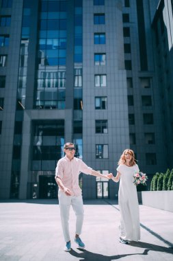 Mutlu genç gelin ve damat şehirde eğleniyor ve yürüyor.                    