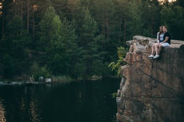 Birbirlerine aşık güzel bir çift. Kucaklaşıp taş üstünde oturuyorlar.         