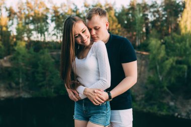 Mutlu genç çift yazın nehir kıyısında sarılıyor..       