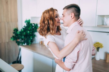 Genç ve güzel bir çift mutfakta sarılıp gülüyor.