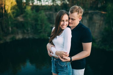 Mutlu genç çift yazın nehir kıyısında sarılıyor..       