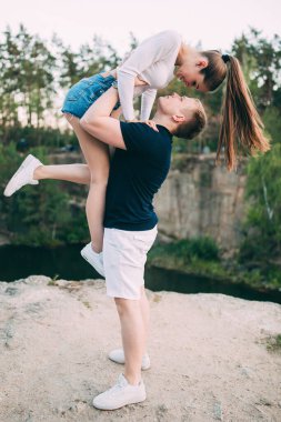 Yakışıklı genç adam güzel kız arkadaşını nehir kenarında taşıyor.