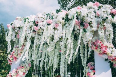 Açık hava düğün töreni için çiçeklerle süslenmiş güzel bir düğün kemeri.                  