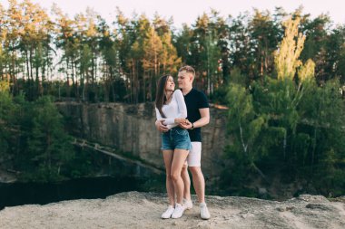 Mutlu genç çift yazın nehir kıyısında sarılıyor..       