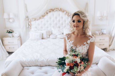 Gelinlikli güzel bir kadın yatak odasında poz veriyor.   