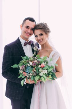 Mutlu ve şık gelin ve damat düğün salonunda buketle                   