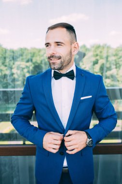 Takım elbiseli ve papyonlu yakışıklı damadın portresi.                 