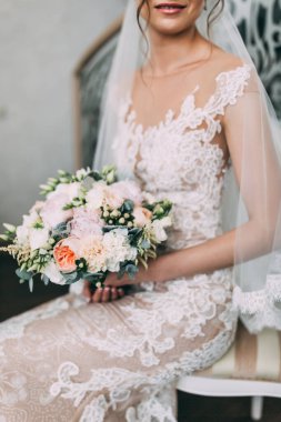 Beyaz elbiseli, düğün buketli, sandalyede oturan güzel bir gelin.       