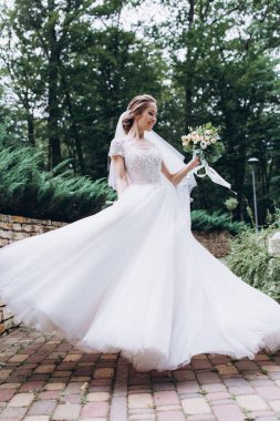 Parkta buketi olan beyaz gelinlik içindeki güzel gelinin portresi.                        