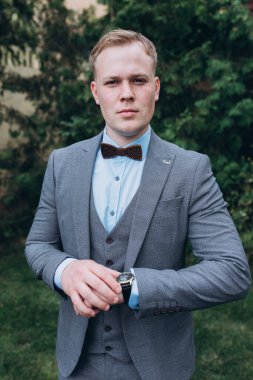 Takım elbiseli yakışıklı genç adam ve dışarıdaki kol saatini kontrol ediyor.       