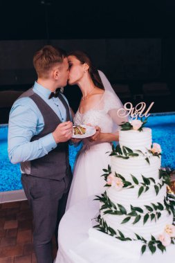 Düğün resepsiyonunda düğün pastasıyla mutlu gelin ve damat       