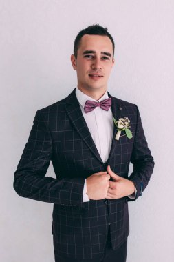 Takım elbiseli ve papyonlu yakışıklı damadın portresi.                 