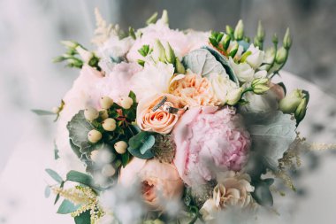 Yüzüklerin yakın görüntüsü ve güzel çiçekli düğün buketi.            