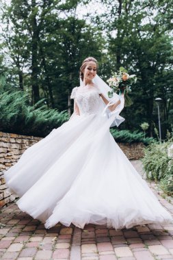 Parkta buketi olan beyaz gelinlik içindeki güzel gelinin portresi.                        