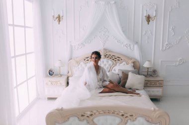 Yatakta poz veren güzel genç bir kadın, gelinin sabahı....       