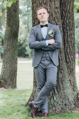 Parkta duran yakışıklı, şık genç damadın portresi.       