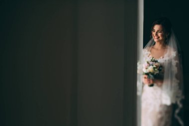 Bir buket çiçekli güzel gülümseyen genç gelinin portresi.