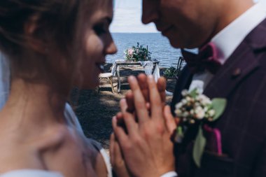 Gelin ve damadın nehir kıyısında yürüyüş ve kumsaldaki masanın yakın görüntüsü.