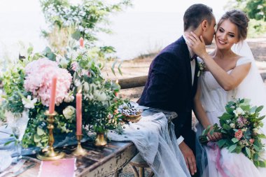 Güzel bir düğün çifti sahildeki masada poz veriyor. Gelin ve damat düğün gününde.                      