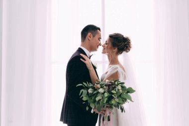 Mutlu ve şık gelin ve damat düğün salonunda buketle                   