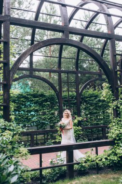 Parkta buketi olan beyaz gelinlik içindeki güzel gelinin portresi.                        