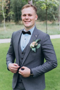 Parkta duran yakışıklı, şık genç damadın portresi.       