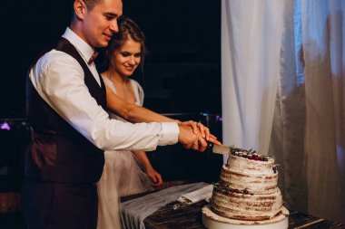 Düğün resepsiyonunda düğün pastasıyla mutlu gelin ve damat       