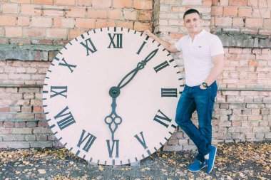 Duvarın yanında saati olan genç bir adamın portresi.