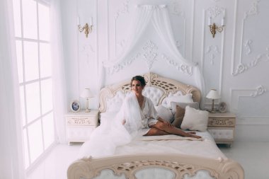 Yatakta poz veren güzel genç bir kadın, gelinin sabahı....       