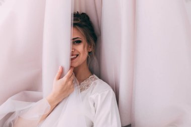 Güzel, mutlu, genç bir gelin yatak odasında gelinlikle poz veriyor. Gelinin özel sabahı..                     