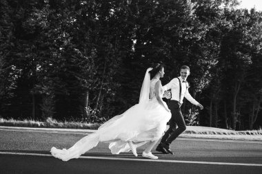 Parkta koşan mutlu gelin ve damadın siyah beyaz görüntüsü